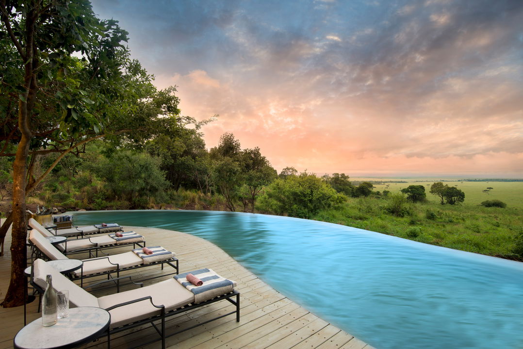 swimming pool with loungers on deck at sunset by andbeyond Bateleur camp Kenya Masai Mara