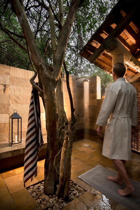 male guest walking to outside shower of suite at andbeyond Bateleur camp Kenya Masai Mara