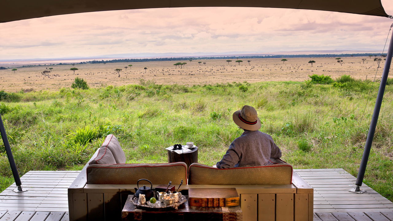 guest on couches of deck with plains view at andbeyond Bateleur camp Kenya Masai Mara