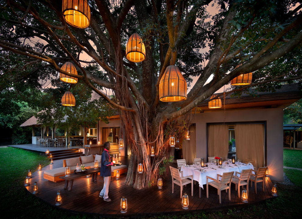 dinner setting under trees on deck at andBeyond Kichwa Tembo Camp Kenya Masai Mara