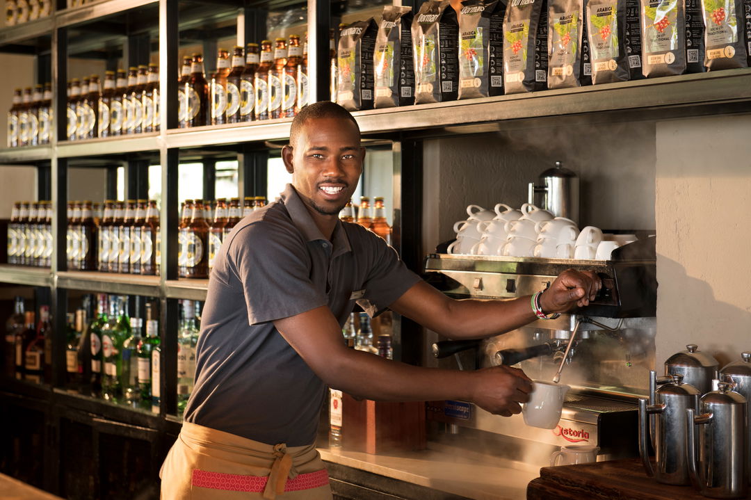 barista making coffee at bar of andBeyond Kichwa Tembo Camp Kenya Masai Mara