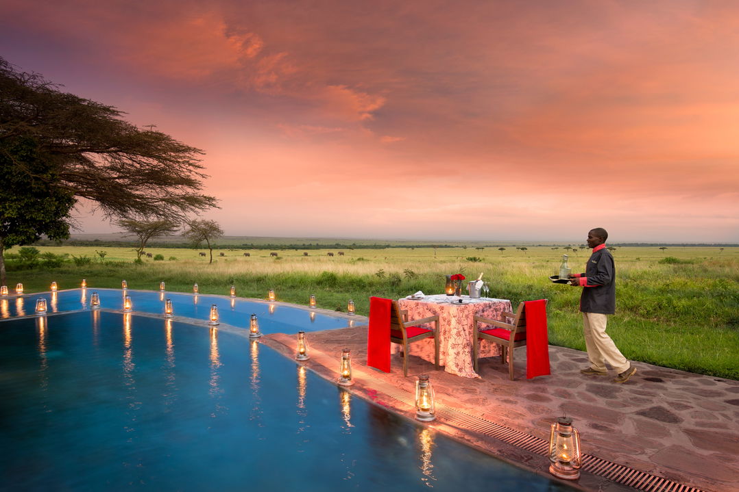 dinner setting by pool at sunset at andBeyond Kichwa Tembo Camp Kenya Masai Mara