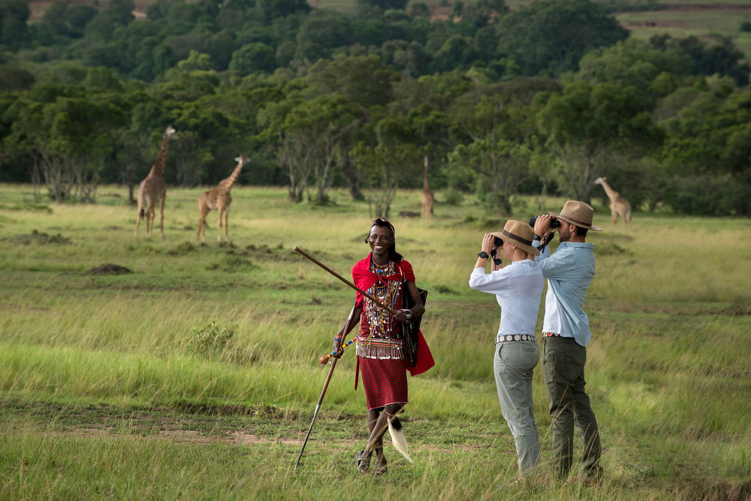 couple with Masai tracker on a walking safari at andBeyond Kichwa Tembo Camp Kenya Masai Mara