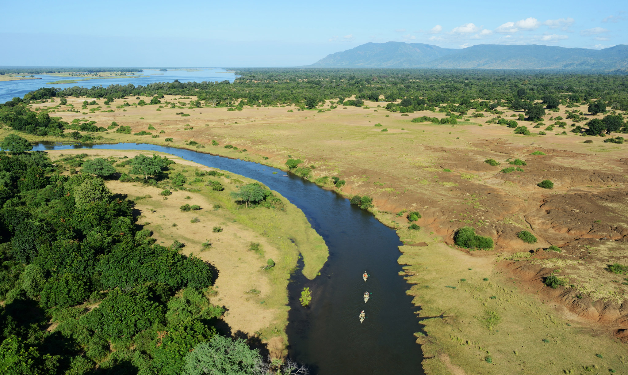 guests in canoes on a river in zambia viewed from above