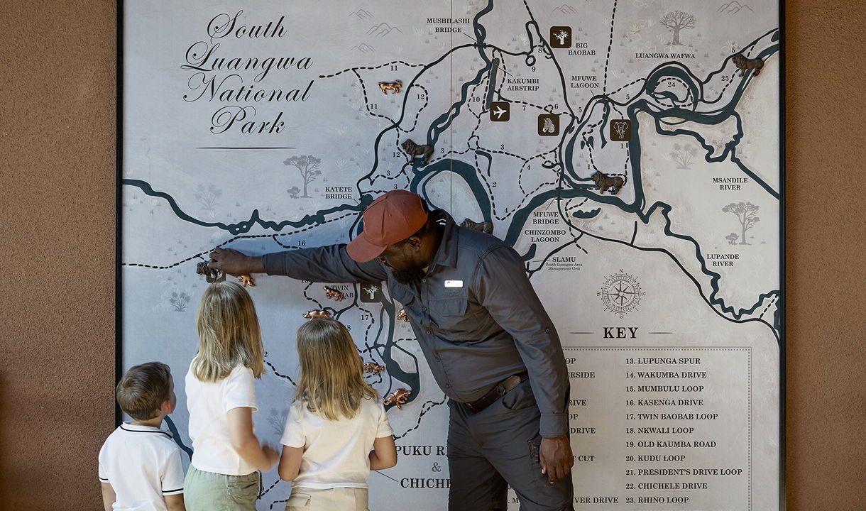 guide showing kids around on map of chichele presidential lodge