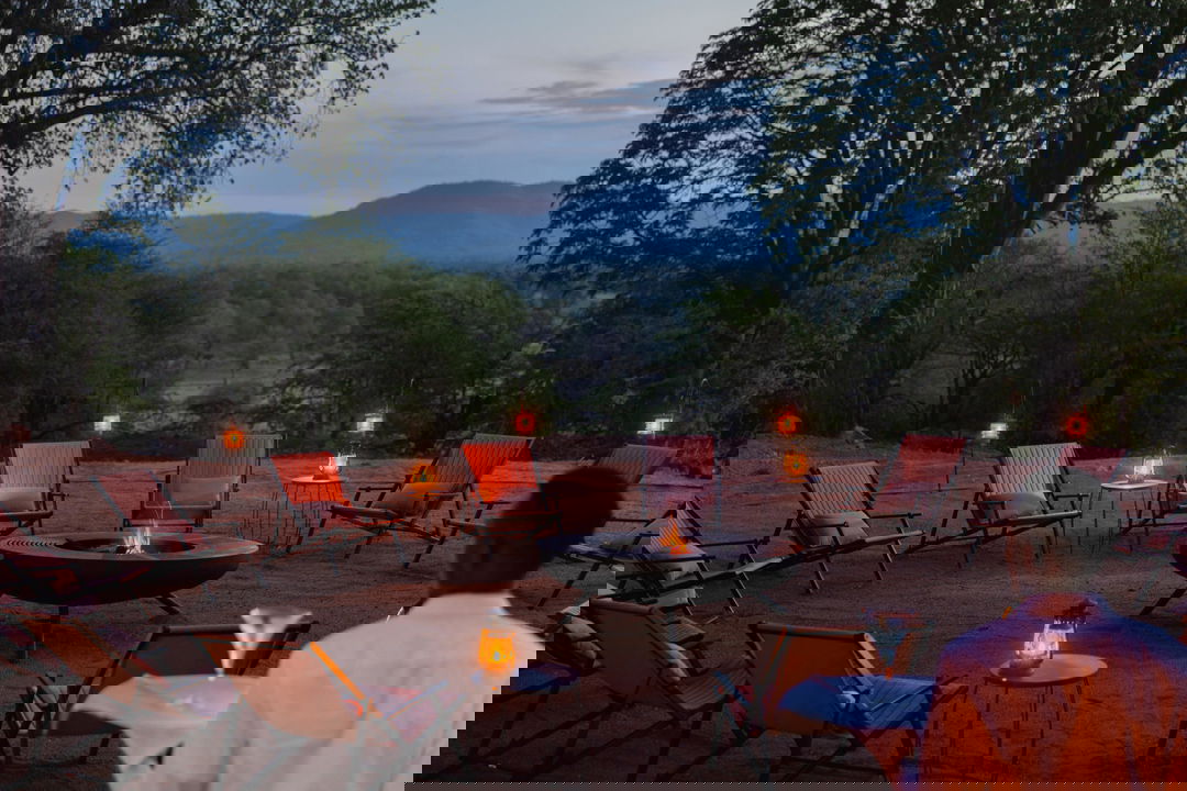 sunset view of fireside boma with chairs and fire at Chichele Presidential Camp Zambia
