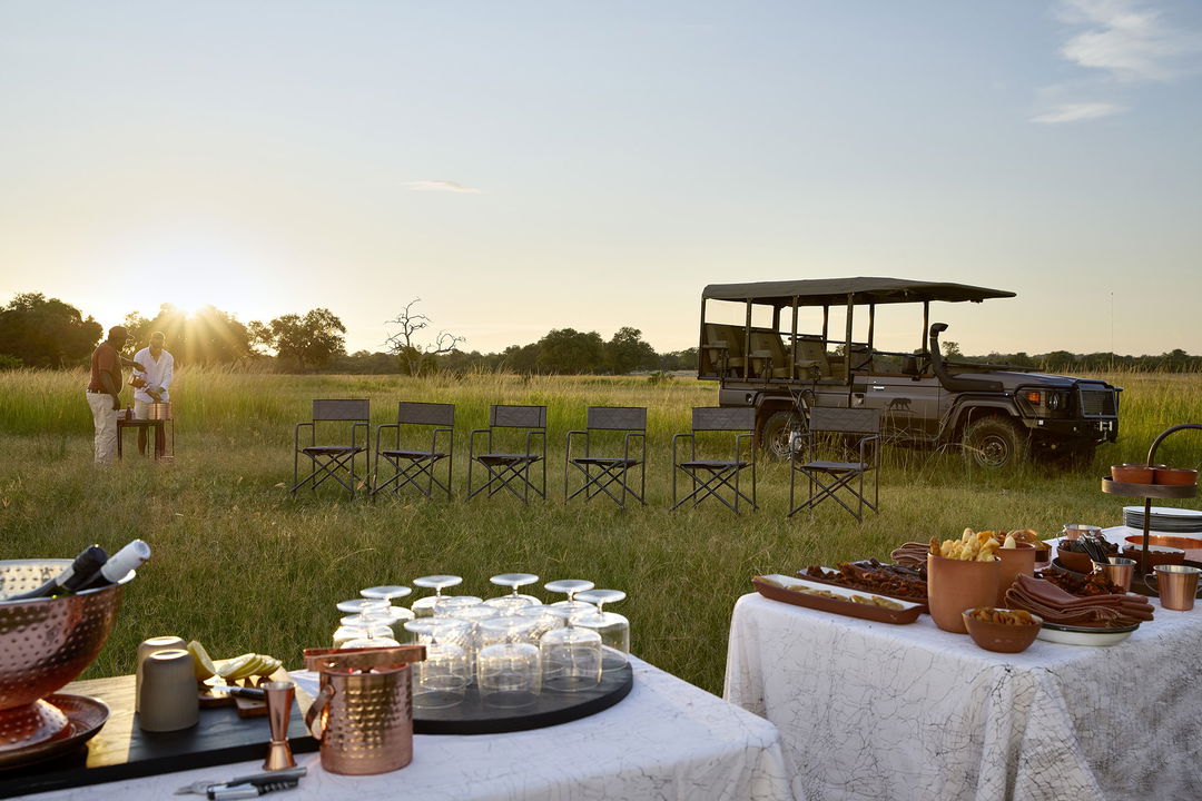 sundowner setting by safari vehicle with tables, chairs and drinks at Chichele Presidential Camp Zambia