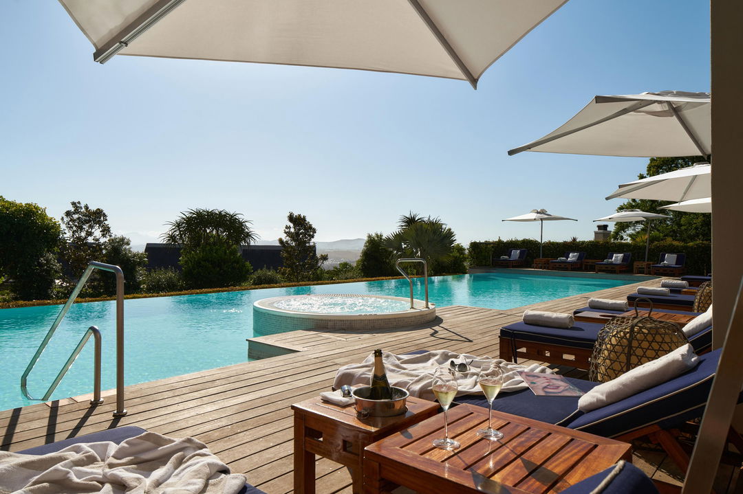 views of pool and loungers on patio of luxury room at Delaire Graff luxury Wine estate in Franshoek