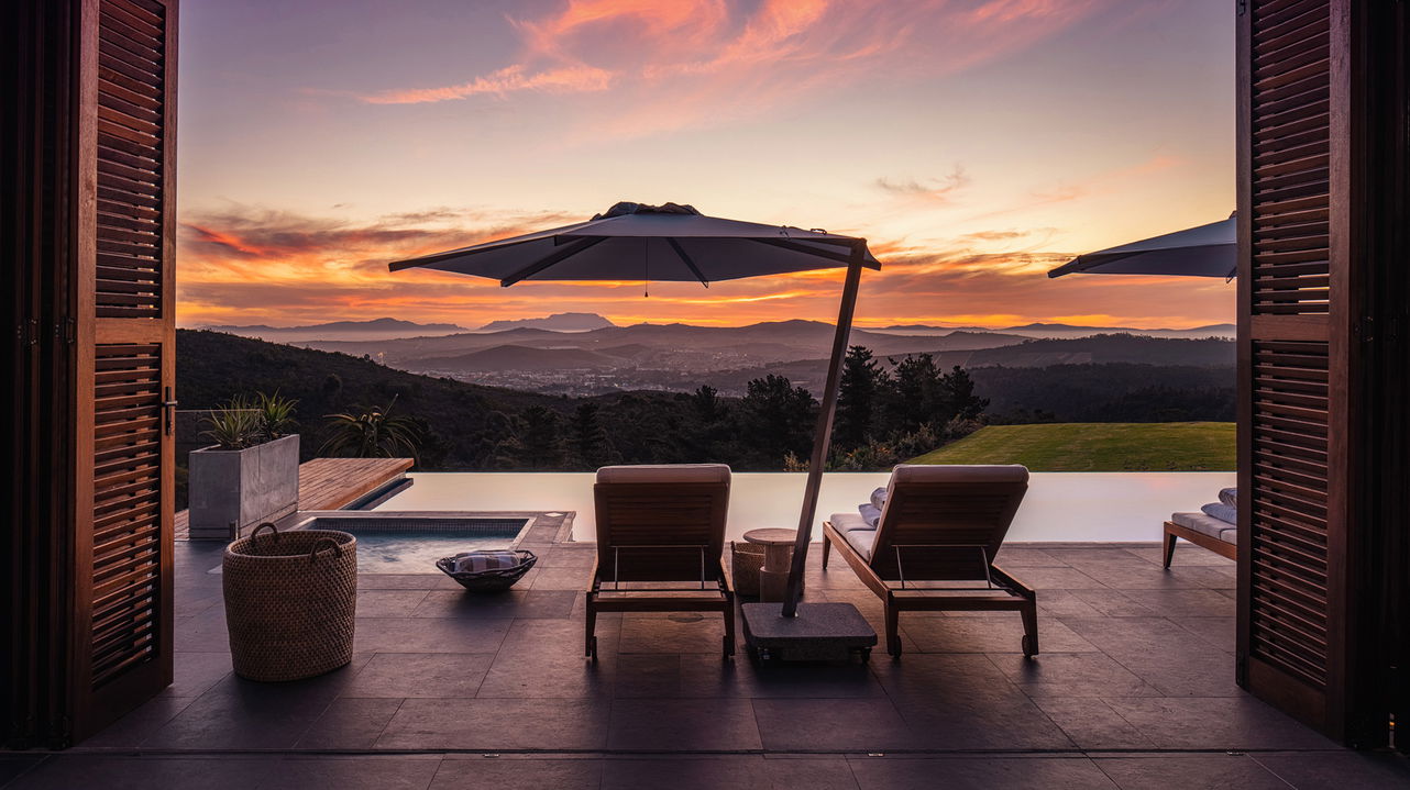 room patio view with loungers by pool and views of mountain at Delaire Graff luxury Wine estate in Franshoek