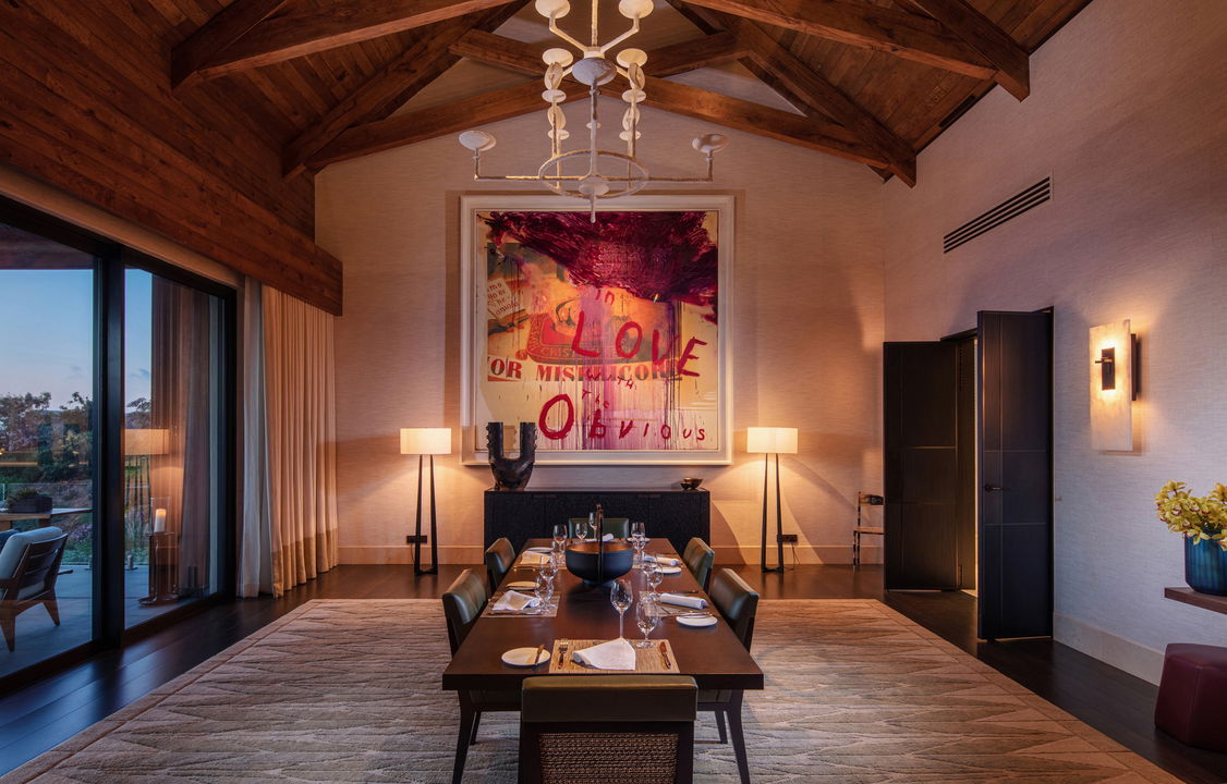 dining table in villa with artwork atpatio from private villa with pool and loungers and mountain backdrop at Delaire Graff luxury Wine estate in Franshoek
