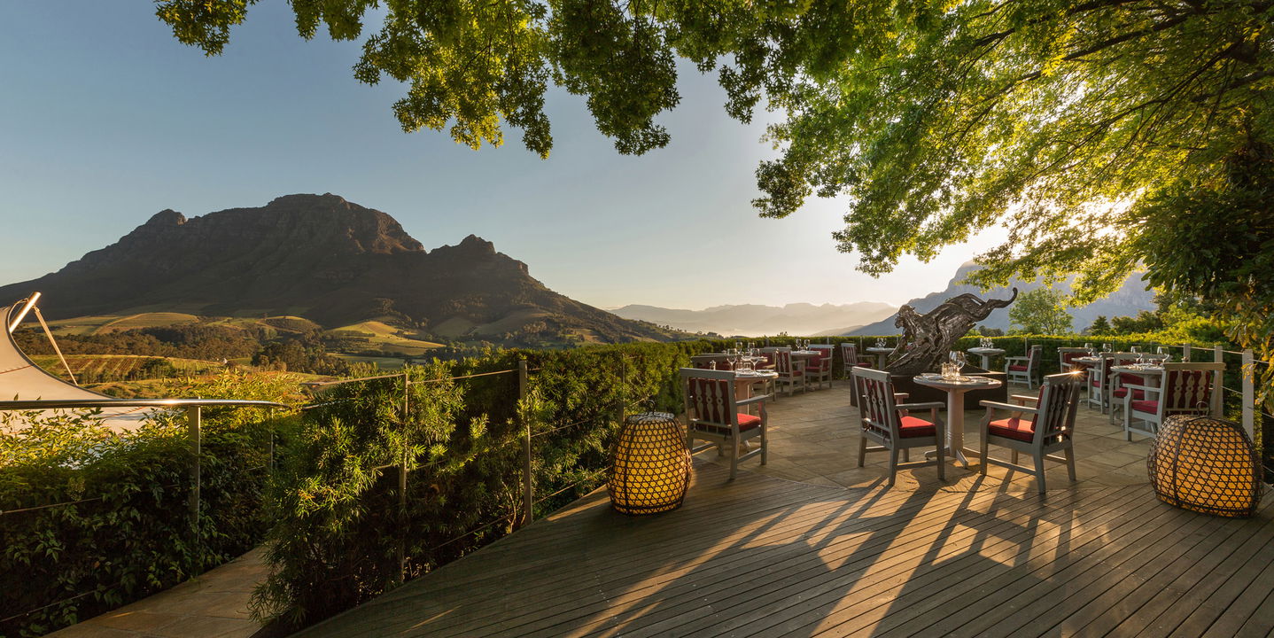 entertainment area with tables and chairs on deck at Delaire Graff luxury Wine estate in Franshoek with mountain in background