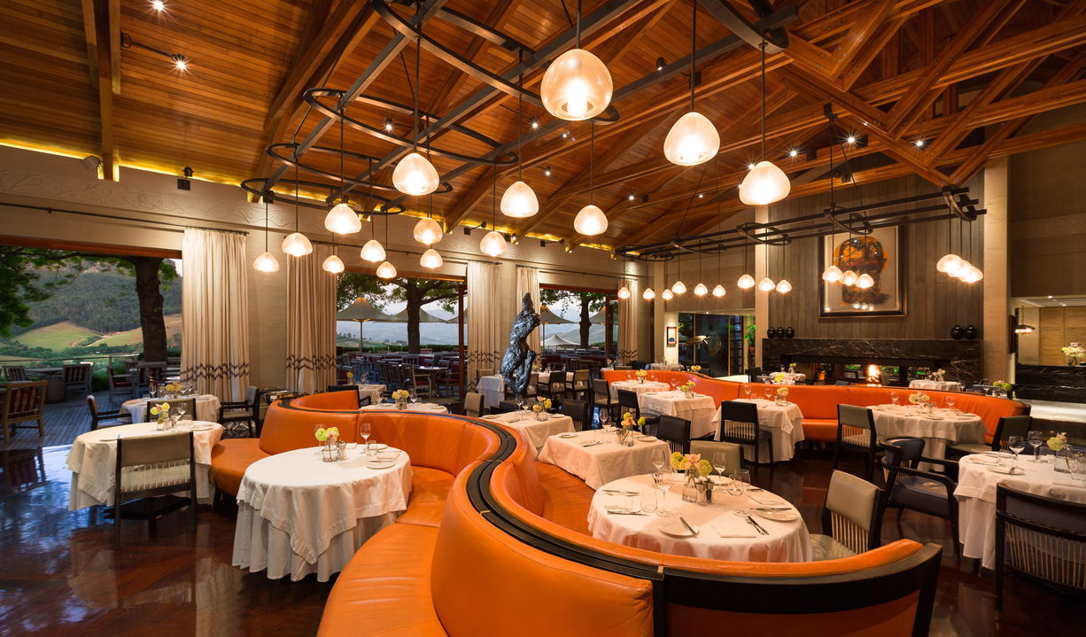 dining couches in orange trim in restaurant at Delaire Graff luxury Wine estate in Franshoek