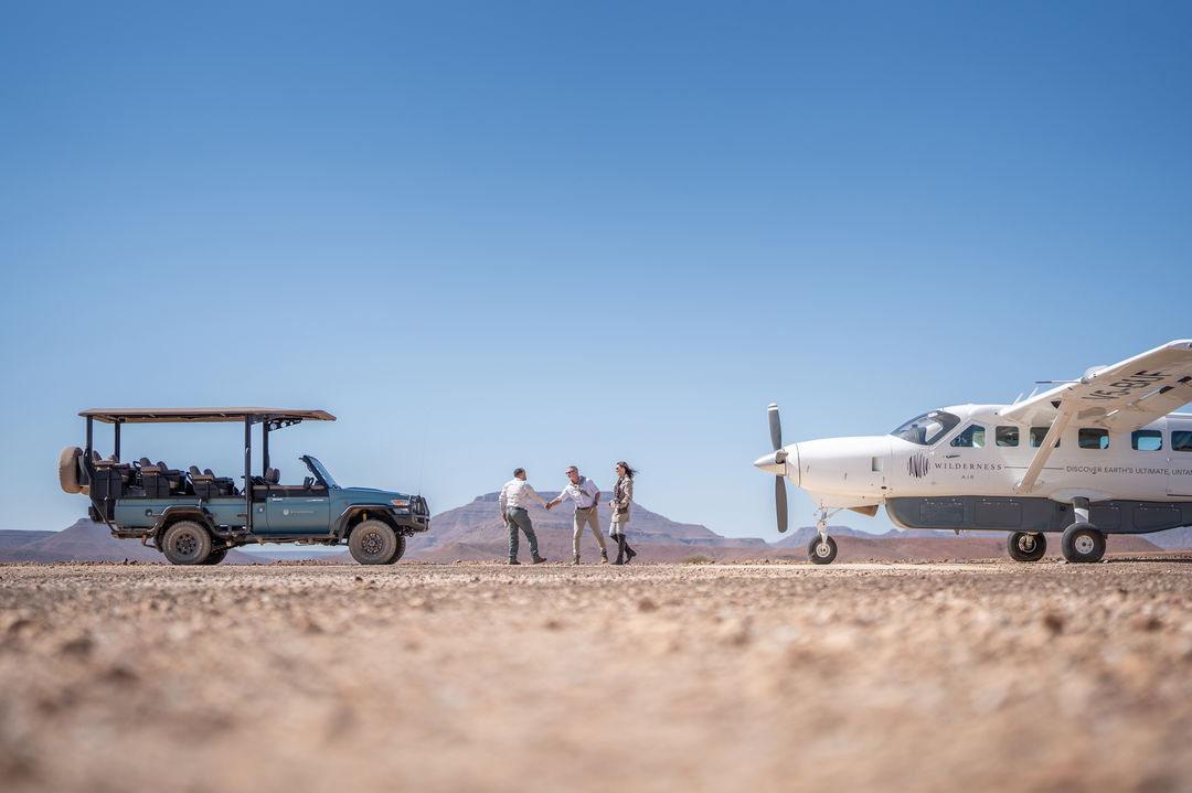 safari vehicle welcoming guests on airstrip at desert rhino camp wilderness Namibia 