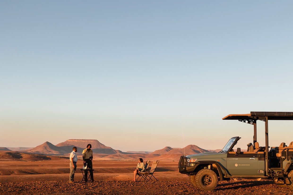 sundowner drinks with guide and safari vehicle at desert rhino camp namibia