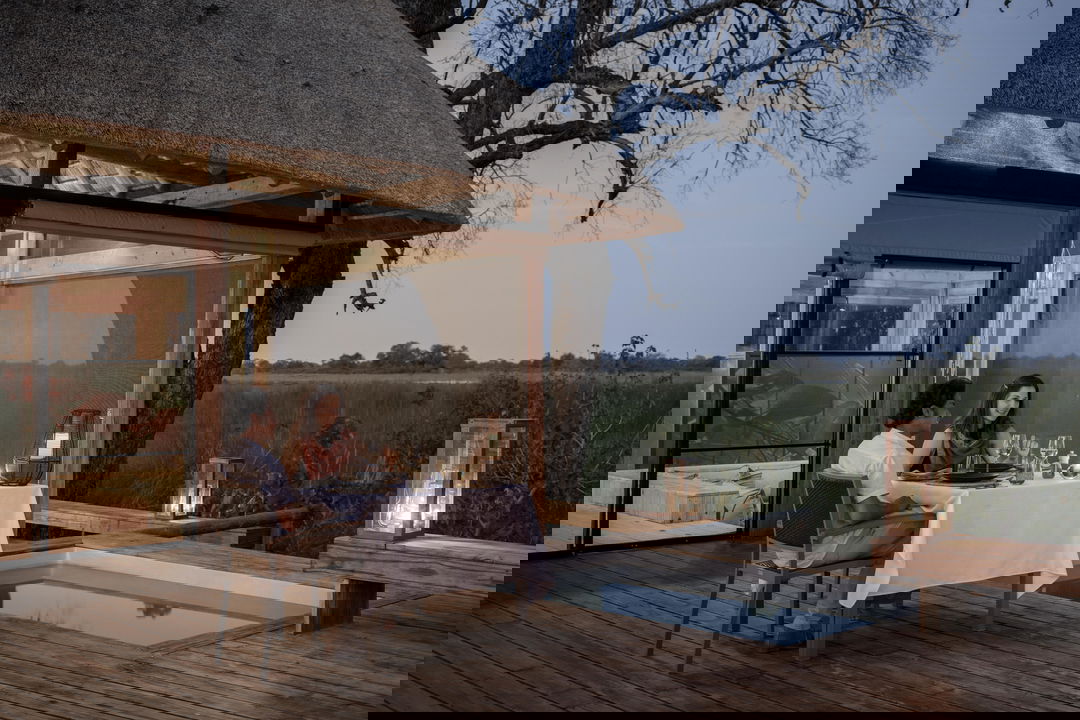 guest sitting at table on deck looking our on planes at Vumbura Plains Camp Wilderness Okavango Delta