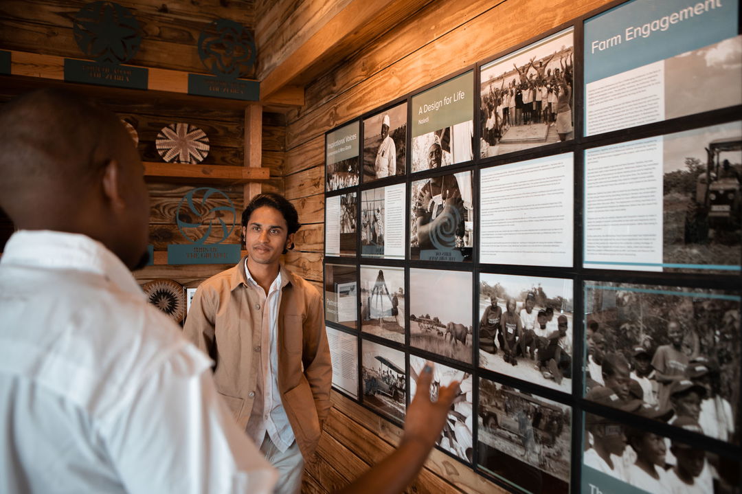 guest in library looking at wall with posters of  Vumbura Plains Camp Wilderness Okavango Delta