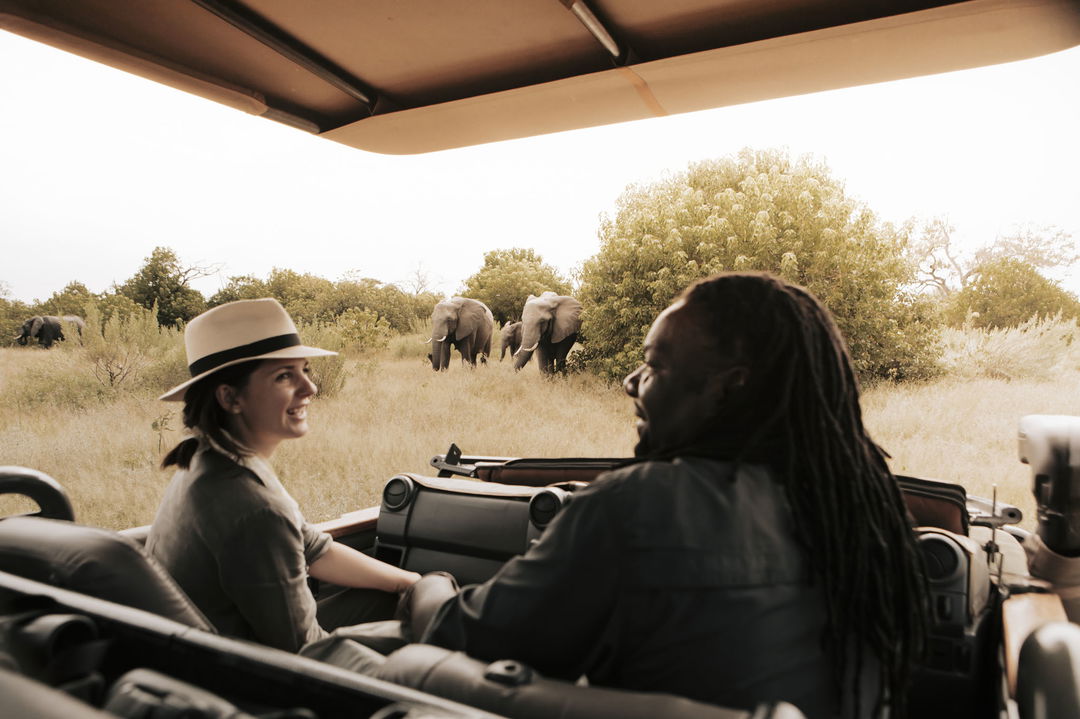 guest and guide in safari vehicle on game drive at Vumbura Plains Camp Wilderness Okavango Delta