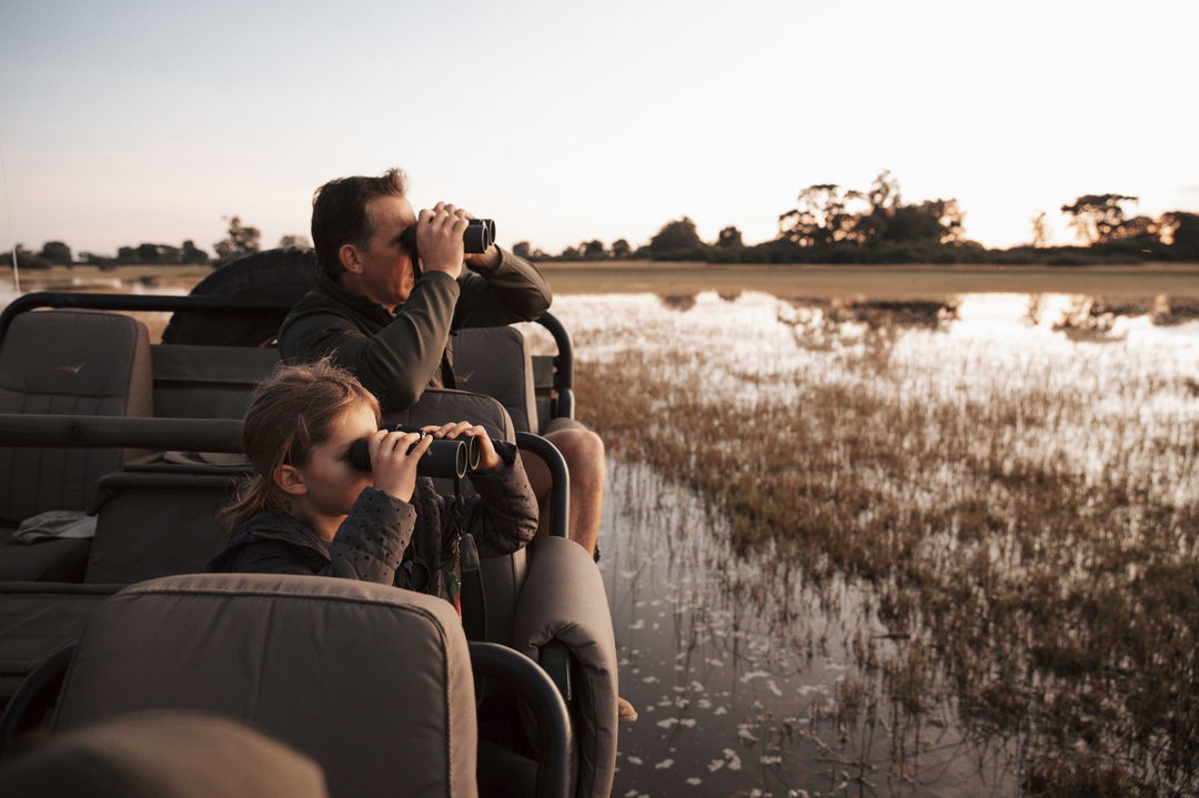 guests with binoculars looking at water plains of Vumbura Plains Camp Wilderness Oka