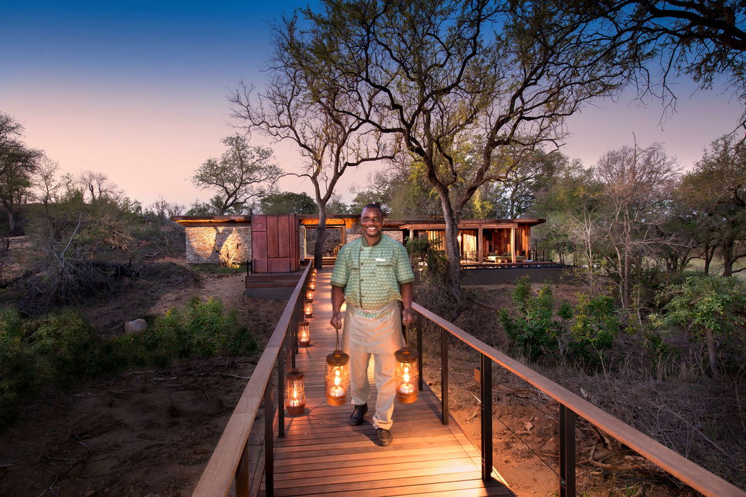 staff carrying lanterns on bridge at &Beyond Tengile River Lodge Sabi Sands