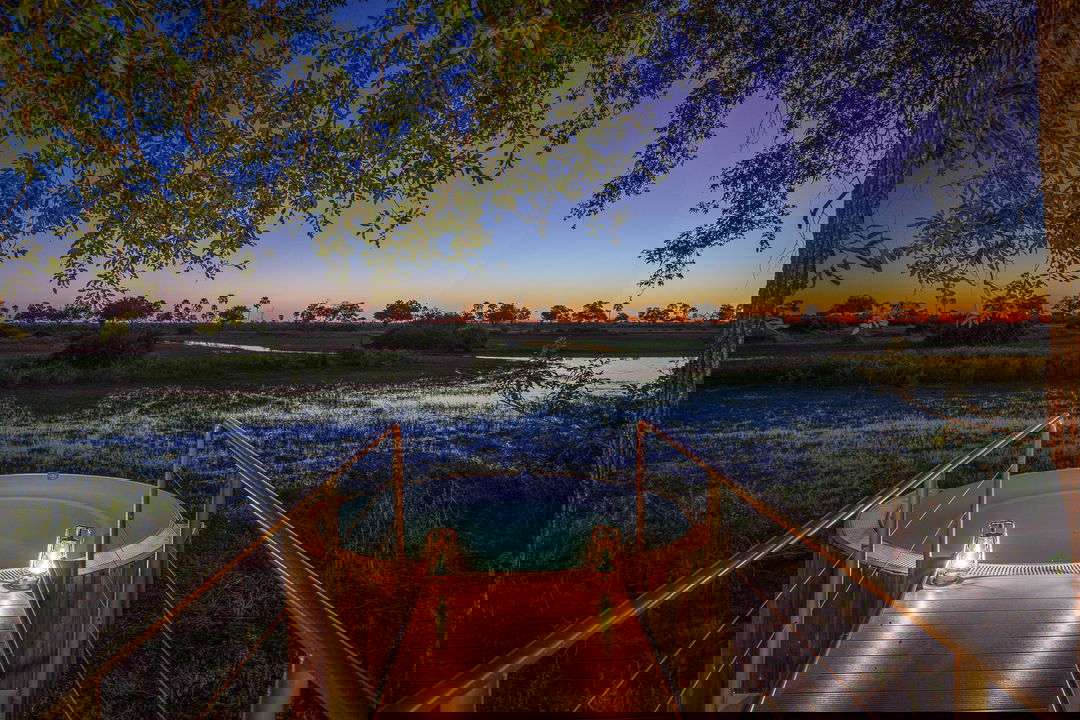 splash pool at night by Jao Camp Wilderness with sun setting on delta in background
