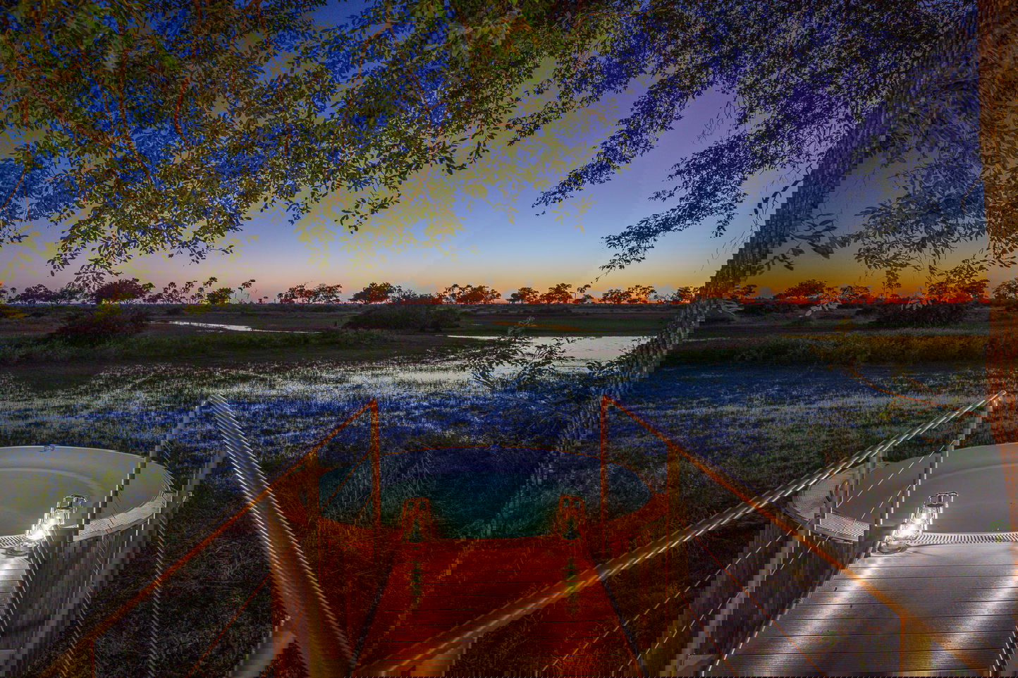 splash pool at night by Jao Camp Wilderness with sun setting on delta in background