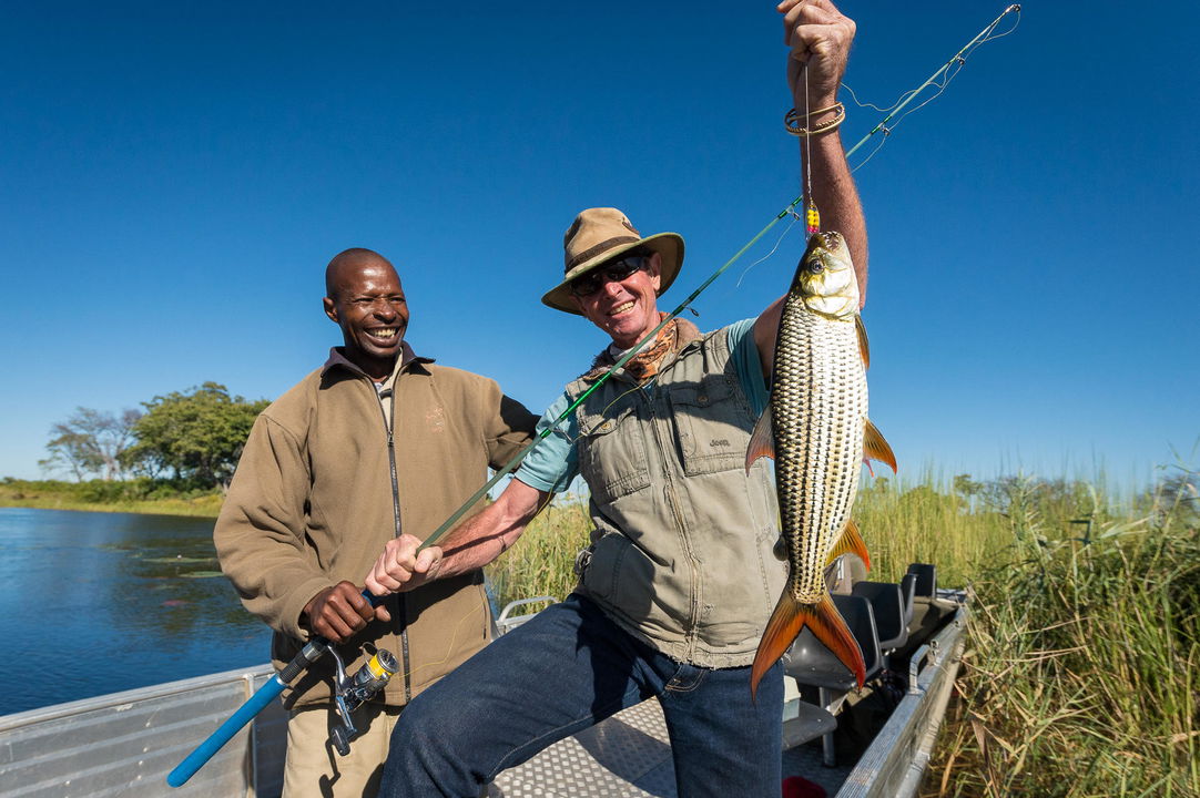 guest holding tigerfish he caught at Jao Camp Wilderness Okavango Delta Botswana