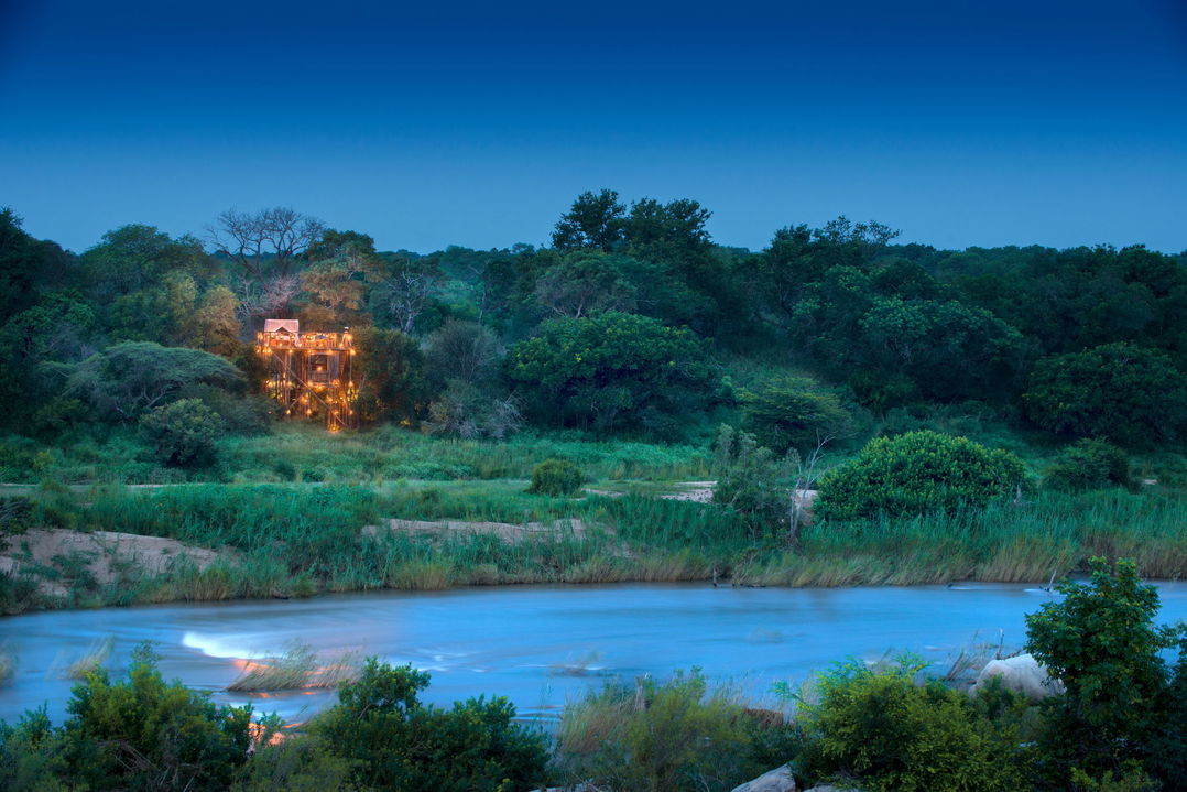 sunset view of Tinyeleti treehouse from across river at lion sands