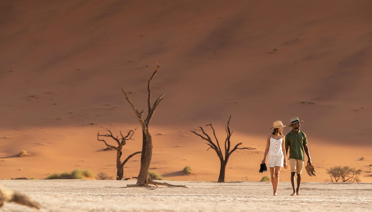 couple walking in sossusvlei namibia between the dunes