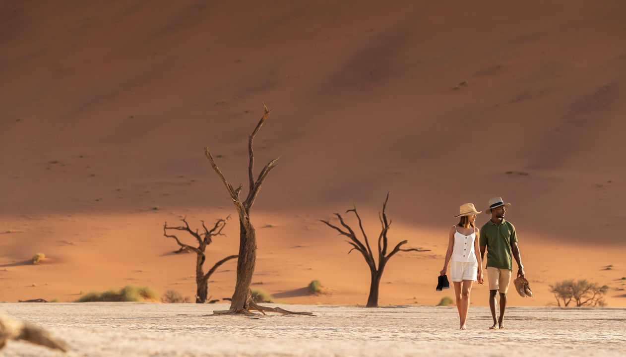 couple walking in the dunes of Sossusvlei at little Kulala camp wilderness Namibia