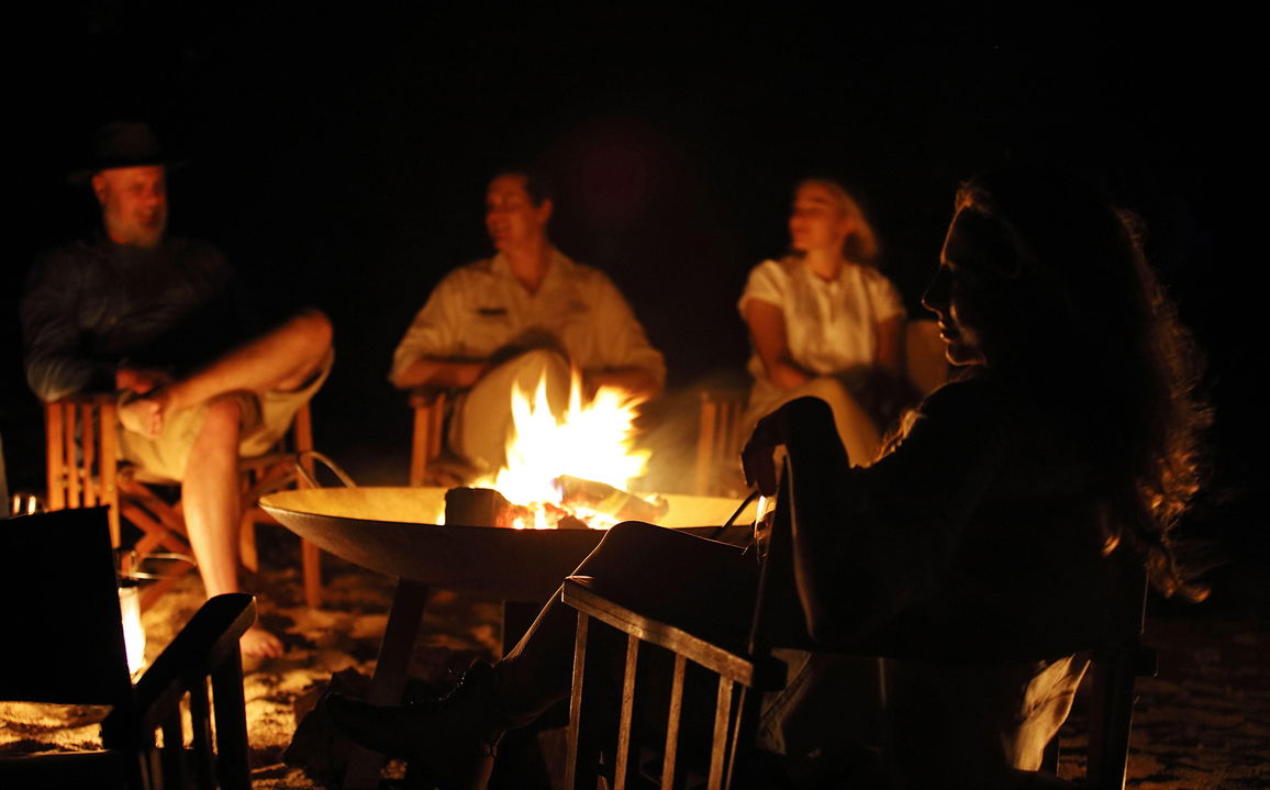 guests around a camp fire by Londolozi game reserve