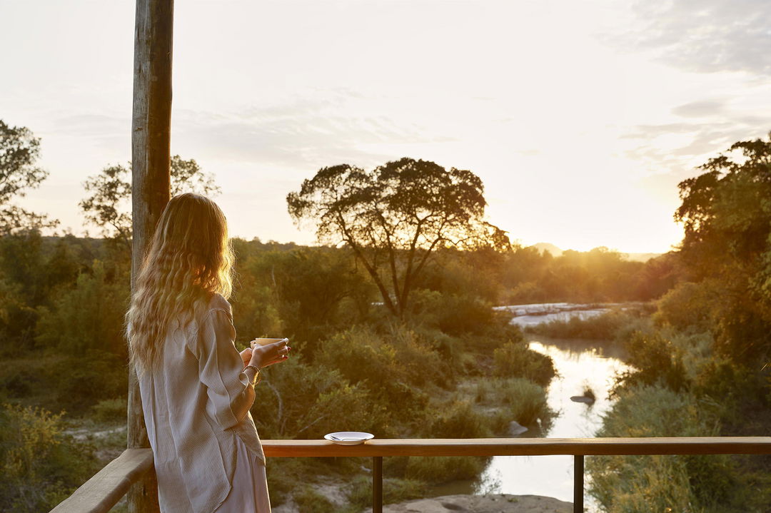 lady guest on main deck of Founders camp at sunset by Londolozi game reserve