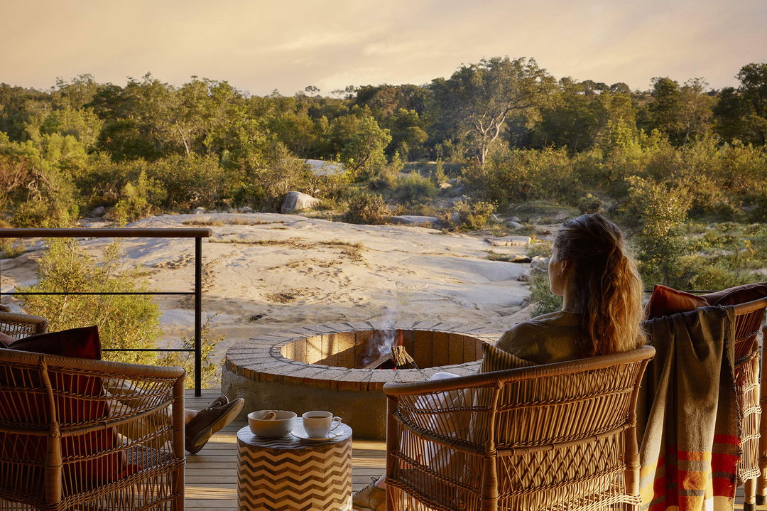 couple sitting by firepit on deck of a suite at Founders camp Londolozi game reserve