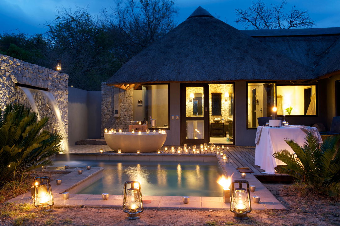 exterior view of illuminated pool and lanterns at Granite suites camp Londolozi