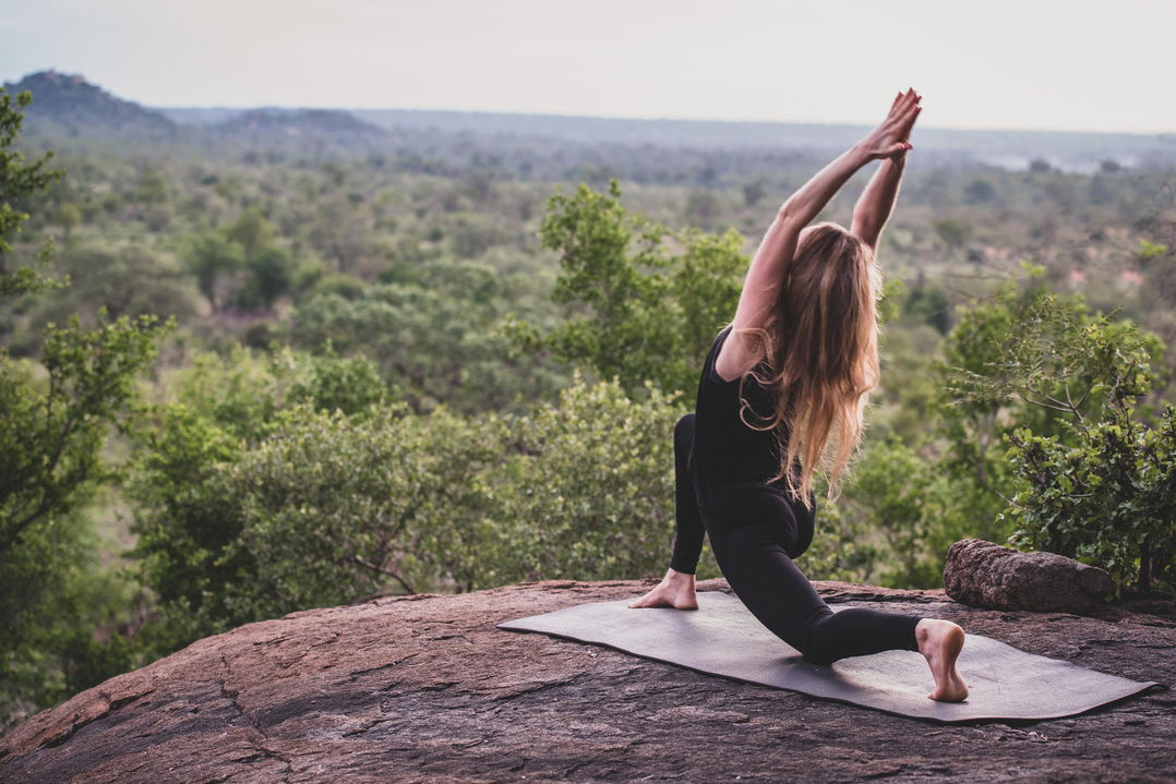 lady guest in a yoga pose on a rock by healing house spa at Londolozi