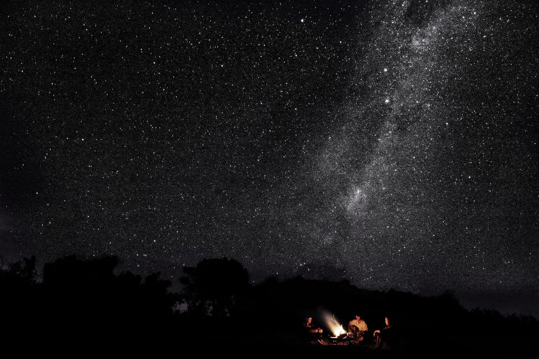 stellar constellations at Londolozi game Reserve at night with guests around campfire