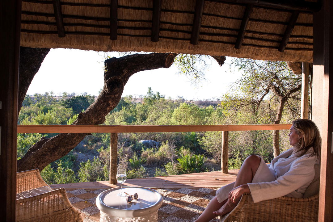lady on deck of a superior chalet by Varty camp Londolozi Game Reserve
