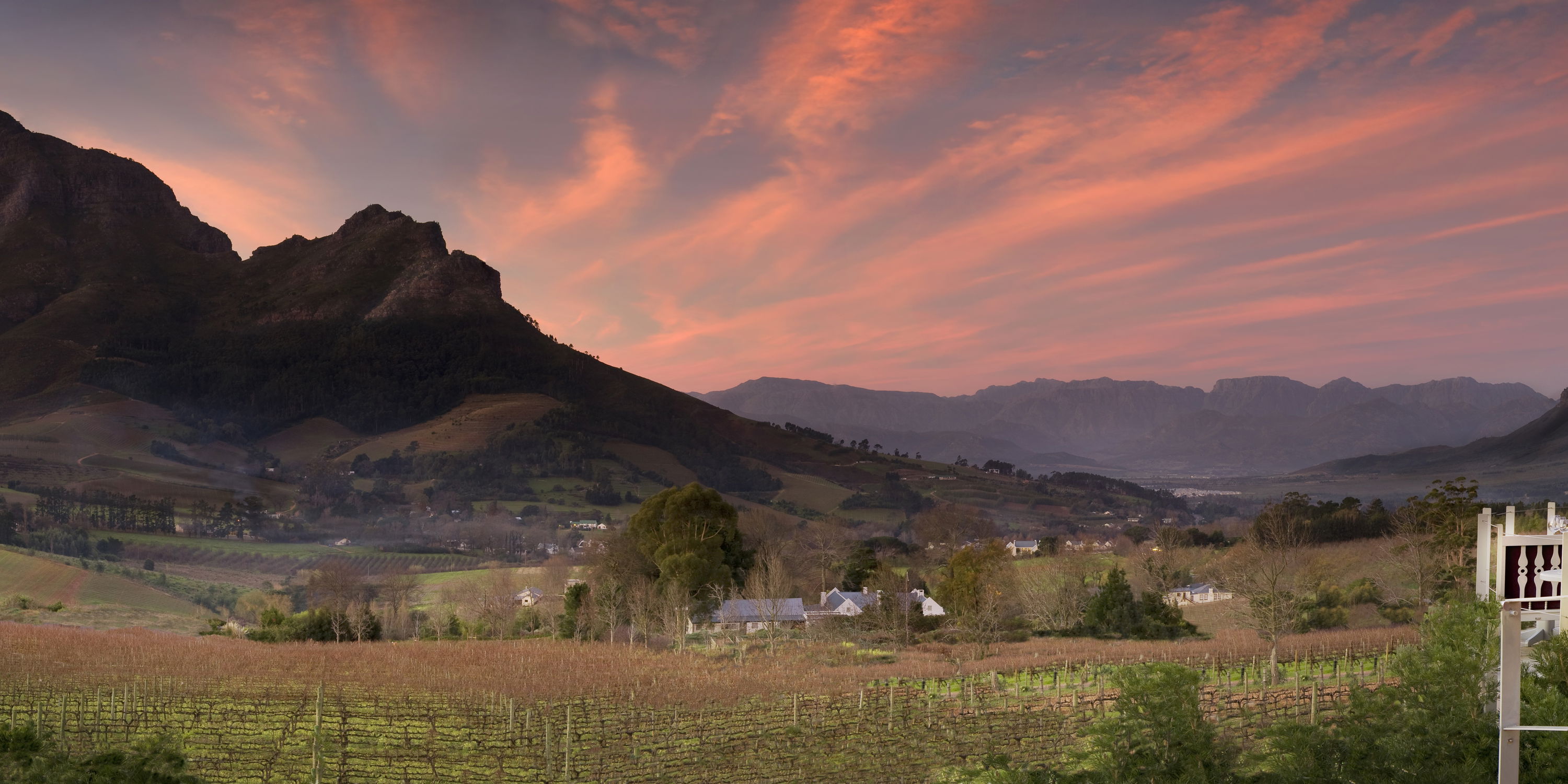 sunset view of Delaire Graff wine estate with tables set for supper and mountains in background
