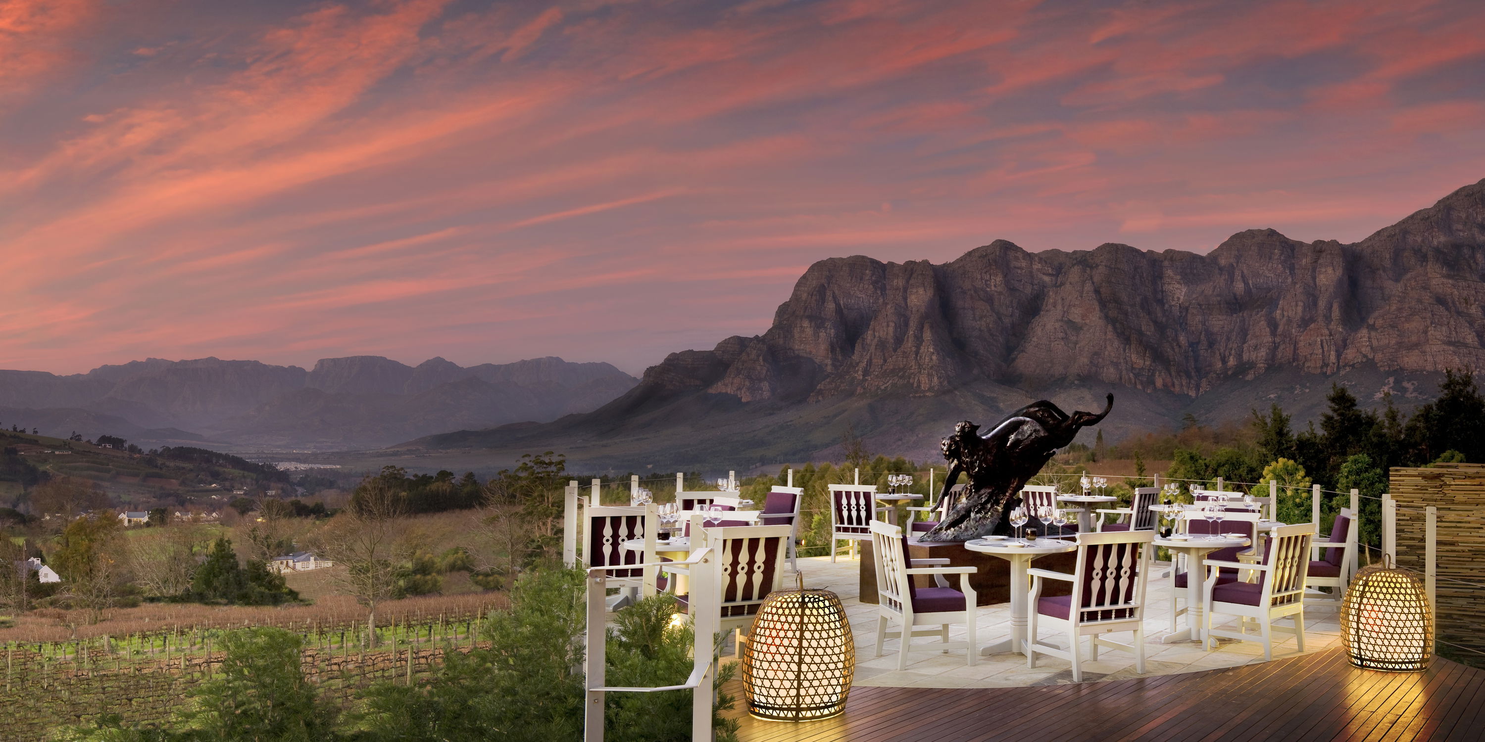 sunset view of Delaire Graff wine estate with tables set for supper and mountains in background