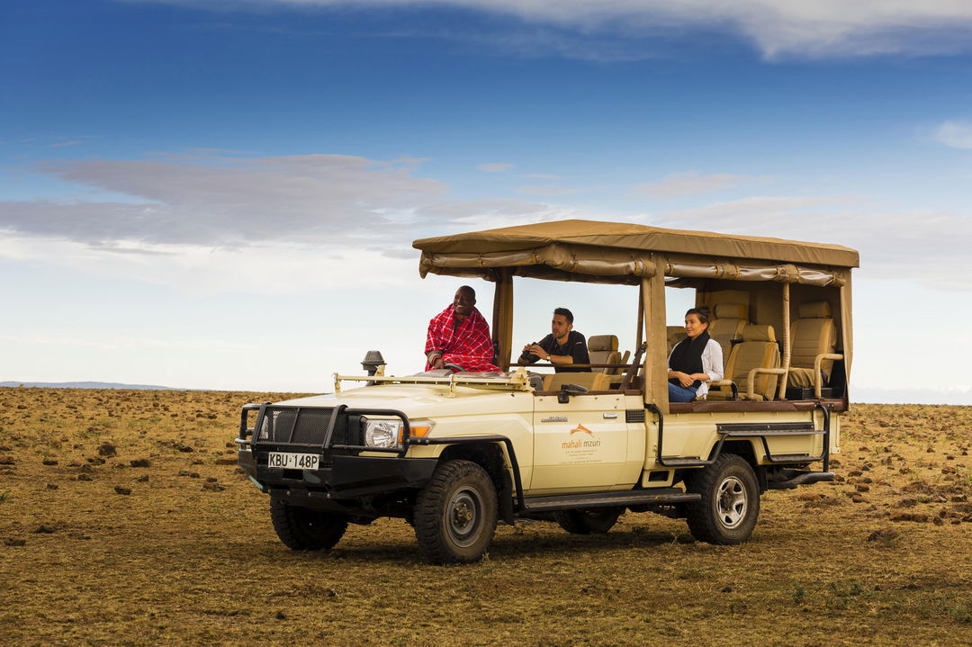 guests on open game drive vehicle on plains of Mahali Mzuri Kenya Masai Mara