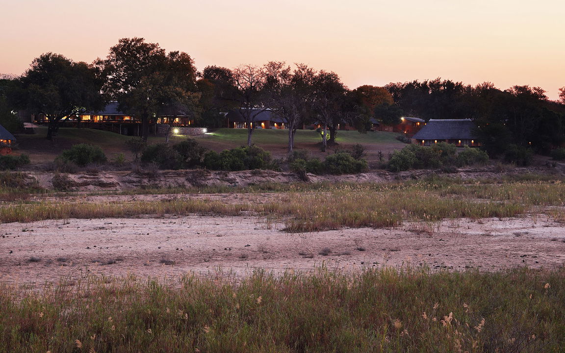 exterior view at sunset from sand river bed at MalaMala Main Game lodge