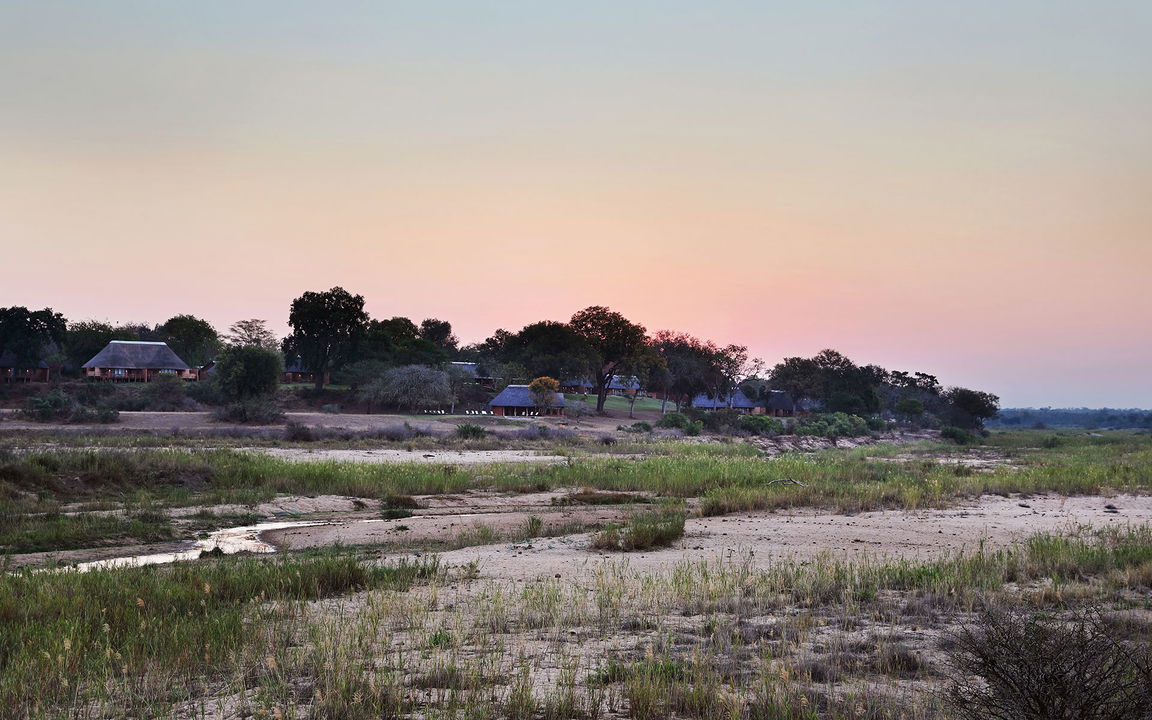 exterior view at sunset from sand river bed at MalaMala Main Game lodge