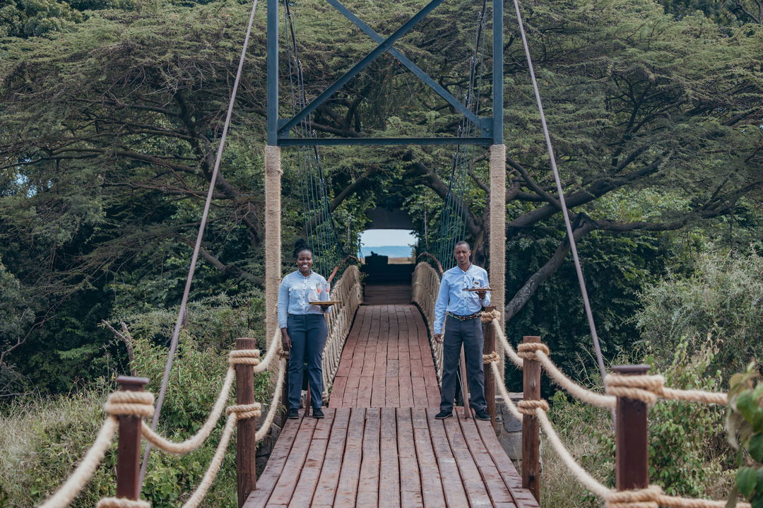 welcoming staff with drinks on bridge of Mara Plains Camp Kenya Masai Mara