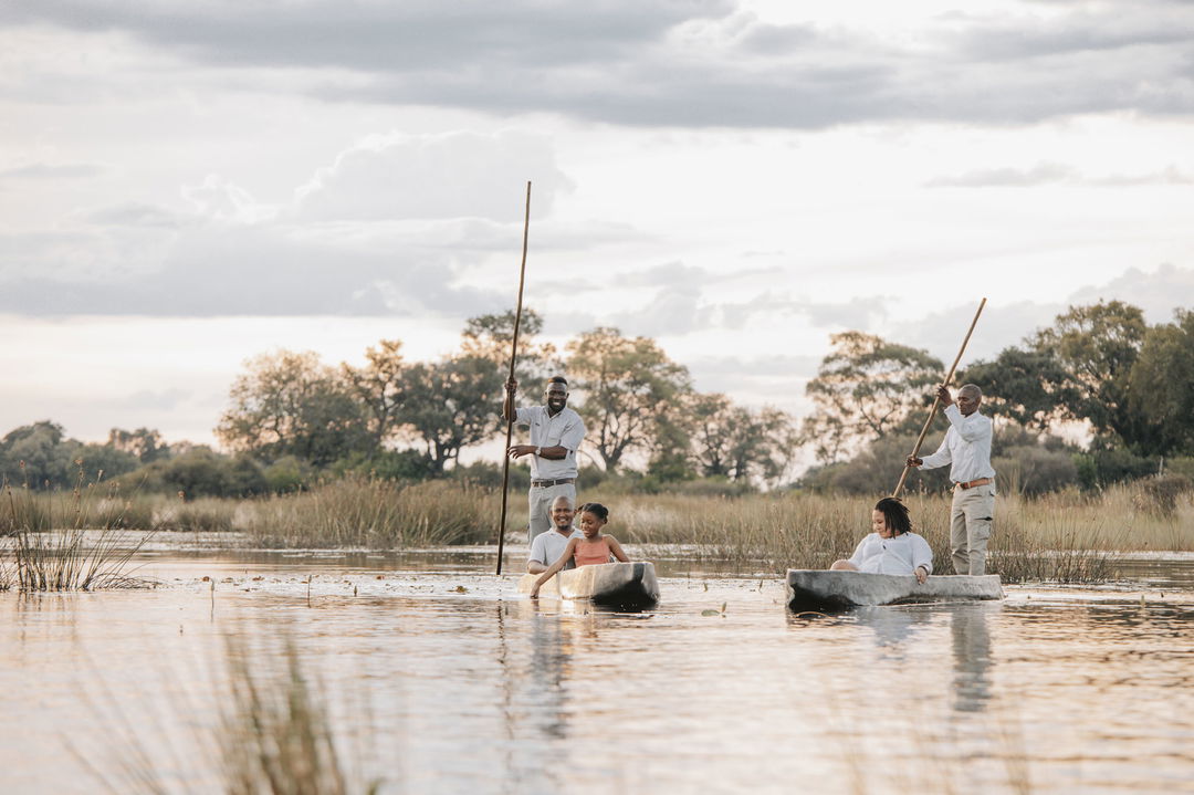 guests and guides in mokoros floating on delta at Vumbura Plains Camp Wilderness Okavango Delta