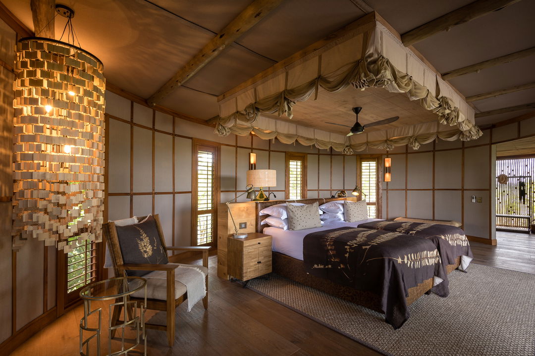 interior view of luxury safari room with bed and chair at Wilderness Mombo Camp