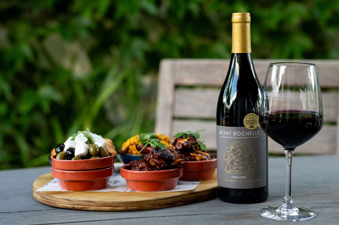red wine and snack bowls on a table at Mont Rochelle Luxury Hotel in Franshoek