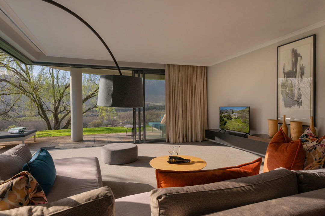 view from a room with couches and open sliding doors at Mont Rochelle Luxury Hotel in Franshoek