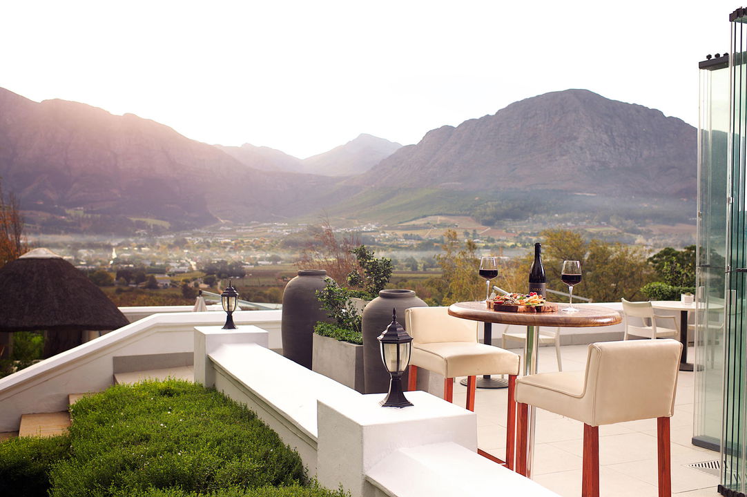 outside patio with mountain views and wine on table at Mont Rochelle Wine Estate