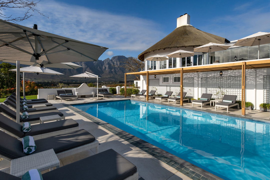 pool area with views and chairs at Mont Rochelle Luxury Hotel in Franshoek