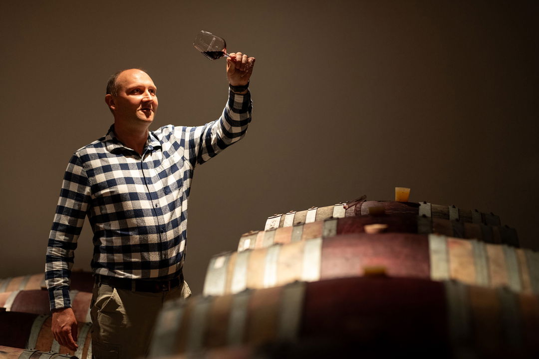 wine maker in cellar by barrel looking at wine in glass at Mont Rochelle Wine Estate