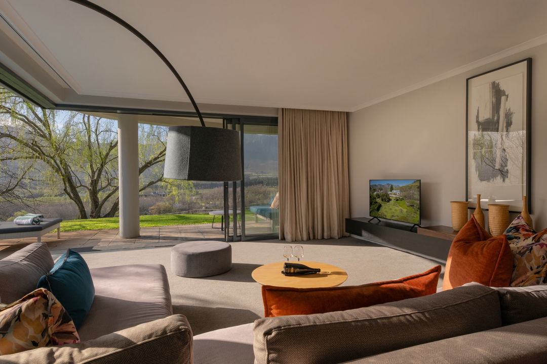 view from a room with couches and open sliding doors at Mont Rochelle Luxury Hotel in Franshoek